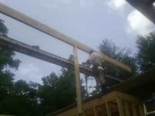 Carpenter setting a ridge beam over a new addition frame — Ice Dam Removal by Roofing Brothers in Garretson
