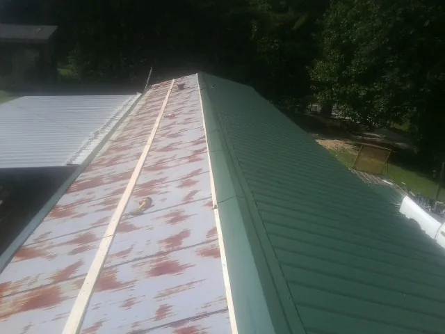 Old rusted panels beside newly installed green metal roofing — Wind Damage Roof Repair by Roofing Brothers in Garretson