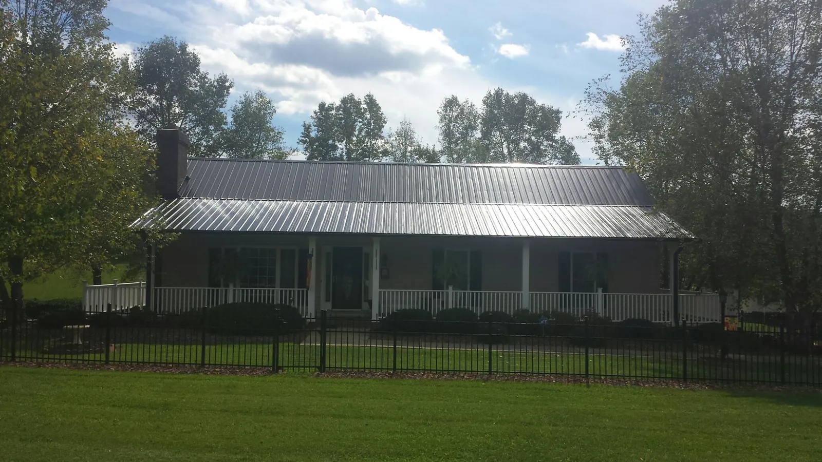 Gray metal roof on a brick ranch with a full width front porch — Gutter Guard Installation work by our crew in Garretson