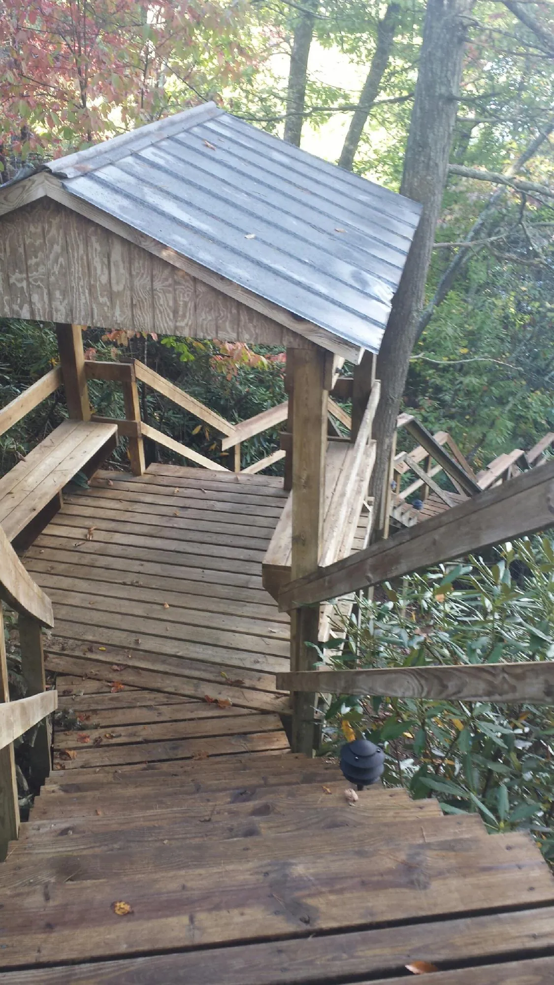 Metal roofed shelter over wooden steps on a wooded walkway — Skylight Repair & Installation work by our crew in Garretson