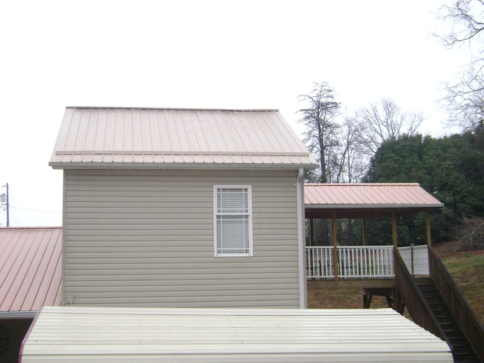 Tan metal roofs on a two story addition and attached porch, from a Roof Replacement job in Garretson