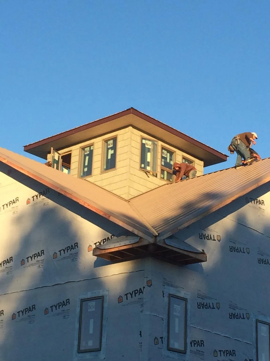 Roofers working around a rooftop cupola on a new metal roof at sunset — Roof Waterproofing in Garretson by Roofing Brothers